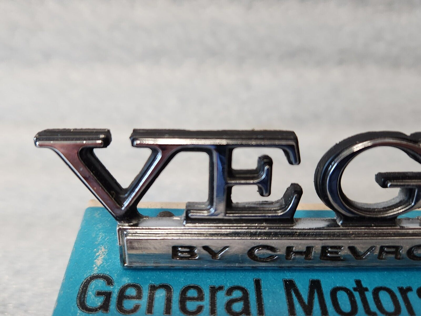 NOS OEM GM 1973-77 Vega Header rear Body Panel Nameplate Emblem 1700895 9633779