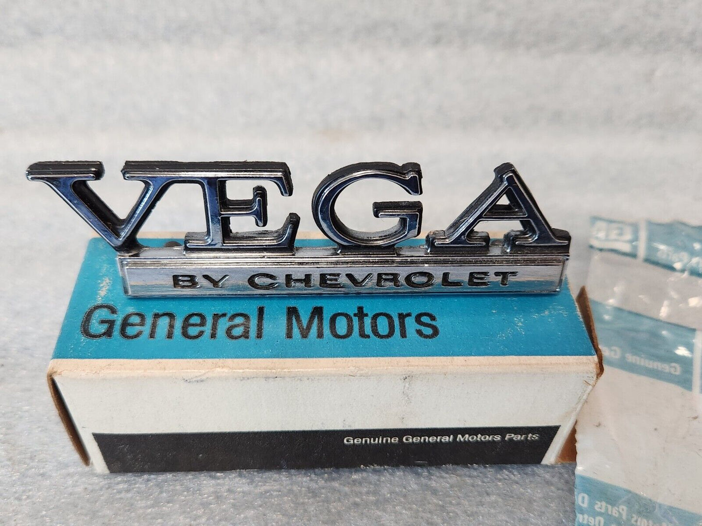 NOS OEM GM 1973-77 Vega Header rear Body Panel Nameplate Emblem 1700895 9633779